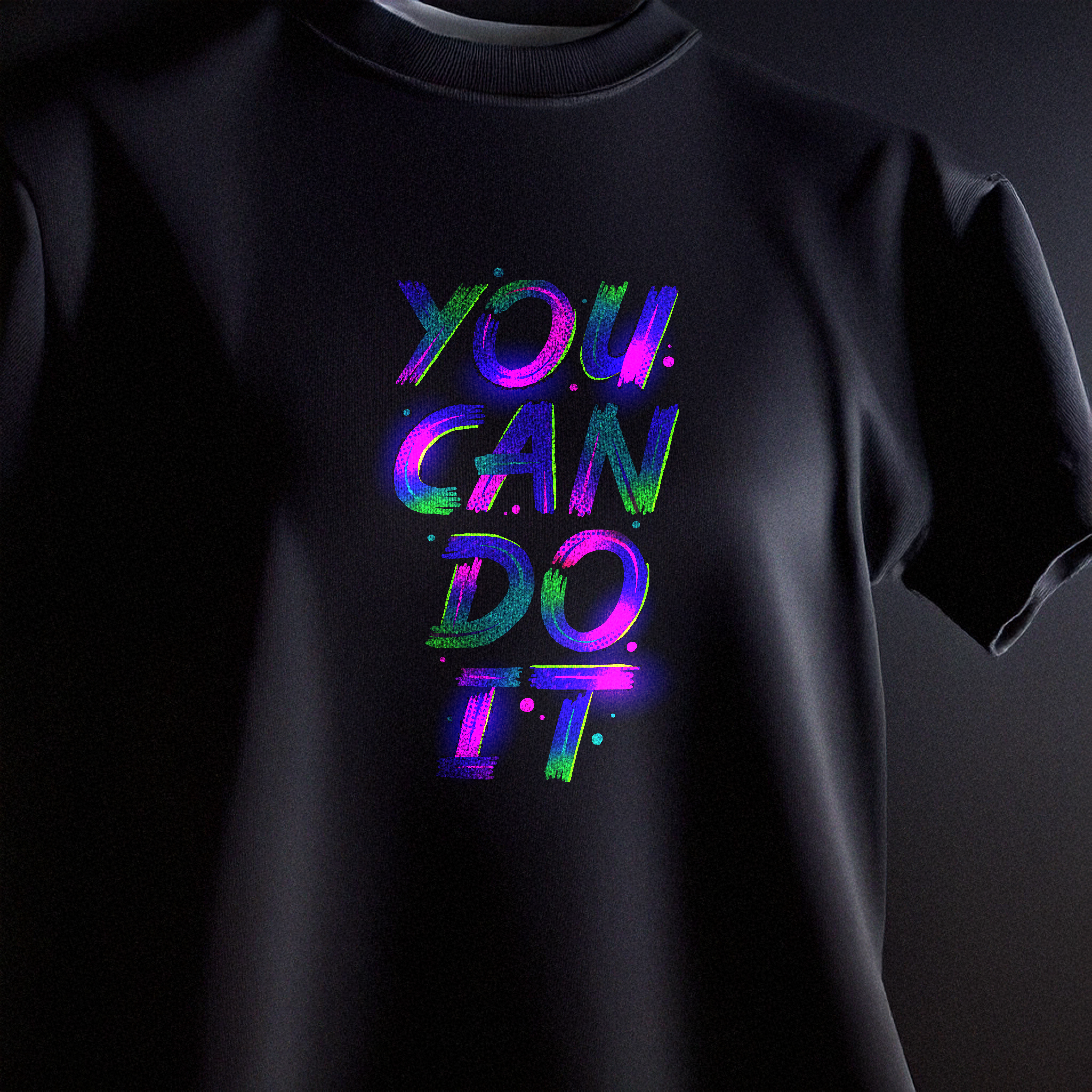Vibrant neon purple and blue 'You Can Do It' typography print on a black t-shirt using Glow in the Dark DTF transfer.